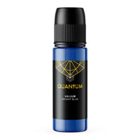 A bottle of Quantum Tattoo Ink - Valium Bright Blue color with a black cap and a black label featuring a gold geometric logo and text, set against a plain white background.